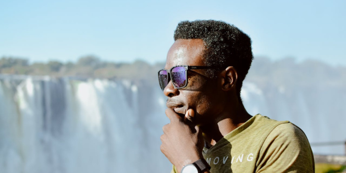 Zambian man with striking eyes wearing sunglasses, admiring Victoria Falls in Zambia.